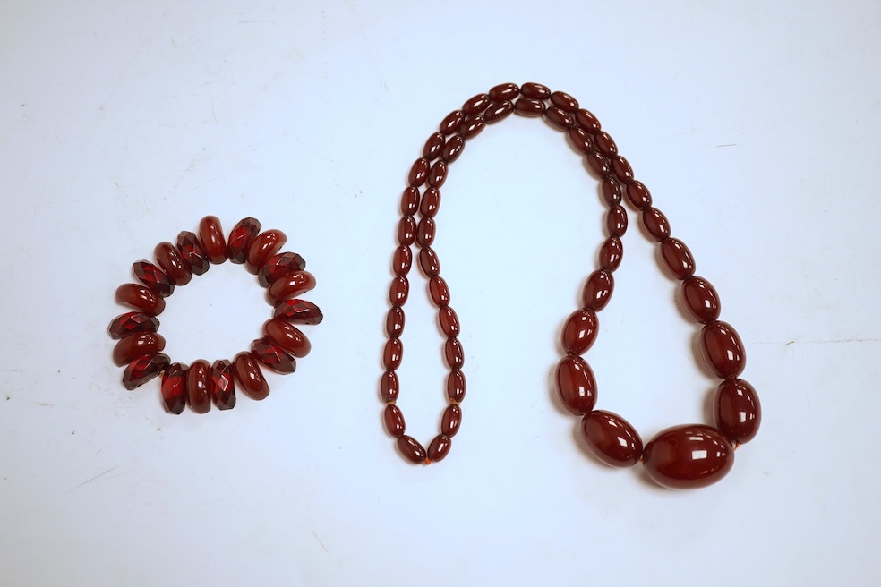 A single strand graduated oval simulated amber bead necklace, 72cm, gross weight 64 grams, together with a simulated cherry amber bracelet.